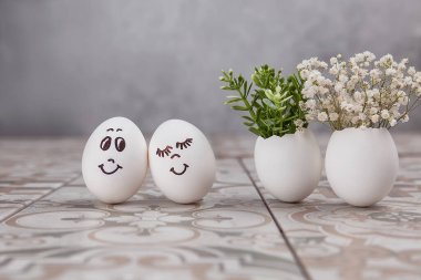 Paskalya kompozisyonu. Masada komik yüzlü beyaz yumurtalar. Yumurtadaki küçük bir buket. Paskalya 'nın asgari konsepti. Yazı için yeri olan bir Paskalya kartı..