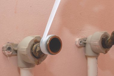 Banyoya su musluğu kuruyorum. Kapatmak için borunun koluna fum bant sarmak. Yakın plan.