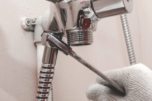 Musluk takılıyor. Tesisatçı musluğu tamir ediyor. Eldivenli adamlar banyo musluğunu tamir ediyor.