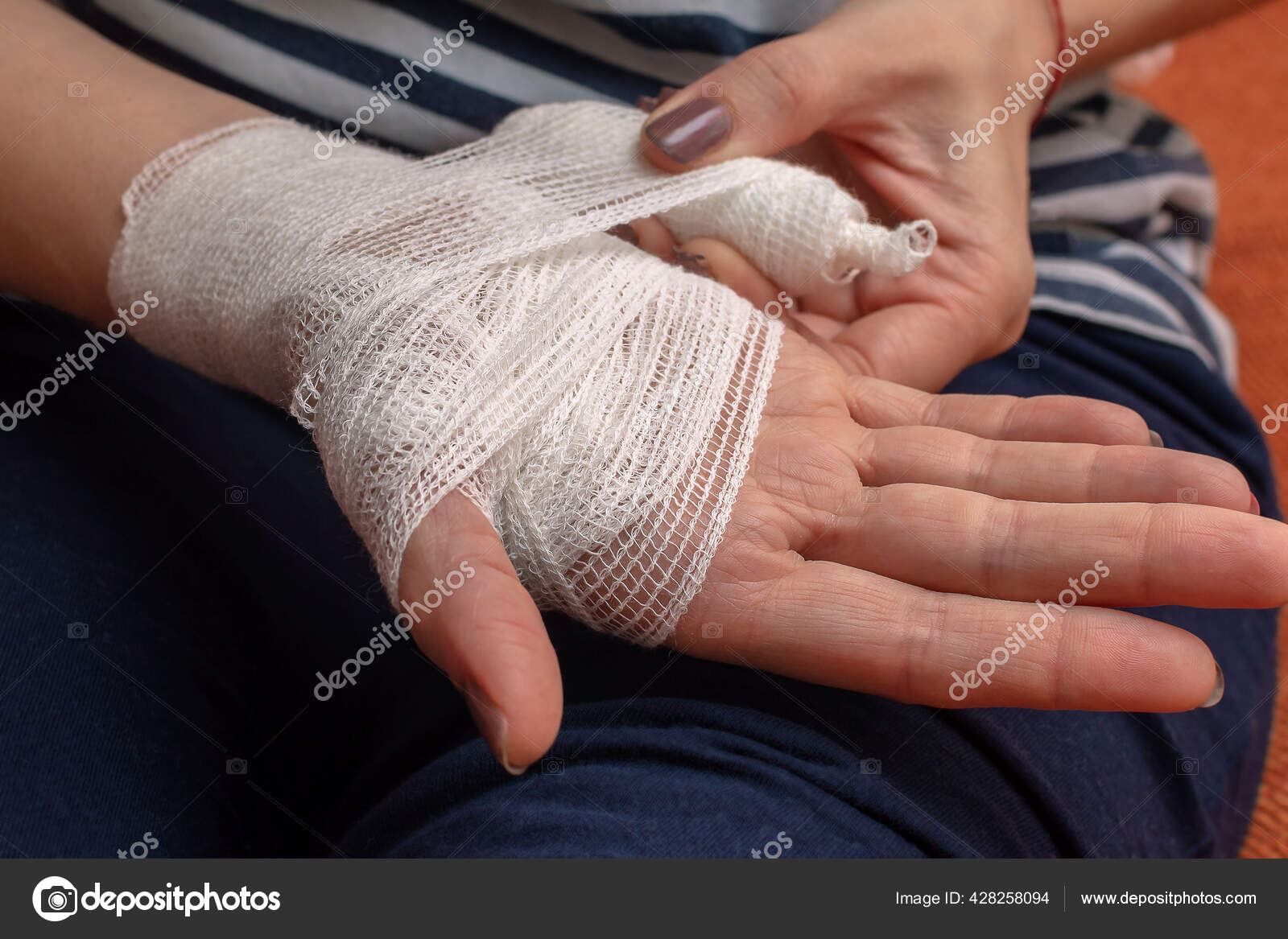 Young woman herself is bandaging upper limb. Bandaging a wrist wound with a  gauze bandage Stock Photo
