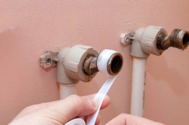 Banyoya su musluğu kuruyorum. Kapatmak için borunun koluna fum bant sarmak. Yakın plan.