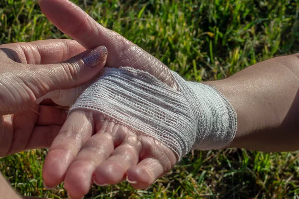 stock image A young woman's wrist, correctly tied with a bandage, is shown. Injured while hiking in the open air. First aid.