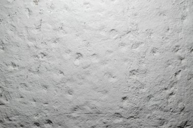 Düzensizlikleri olan beyaz desenli bir duvar yukarıdan bir avize ile aydınlatılır..