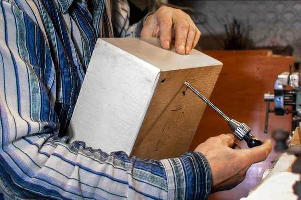 Egy idős ember kezei, aki egy fadobozt javít egy műhelyben. Idős asztalos egy szerszámmal. Nyugdíjas szenvedély — Stock Fotó