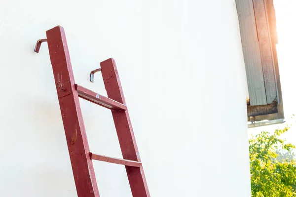 Wooden stepladder against the wall. Repair in the summer, on a sunny day. Facade work at the rural house — Stockfoto