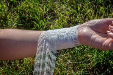 Genç bir kadın, düştükten sonra bileğine antibakteriyel bandaj uygular. El yaralanmasından sonra ilk yardım.