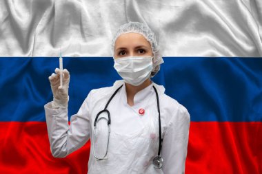 Rusya bayrağının arka planında tıbbi üniformalı genç kadın bir şırınga taşıyor. Yeni koronavirüs aşısı kavramı, koronavirüs COVID-19 aşısı.