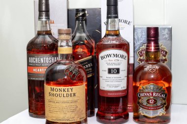 Minsk, Belarus - Eylül 2020 - arka planda beyaz bir masada birkaç şişe popüler ve ünlü viski standı. Chivas Regal, Bowmore, Monkey Shoulders, Johnnie Walker markaları.