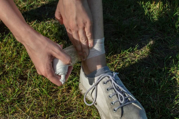 Ao ar livre, os tendões nas pernas de uma jovem são envoltos com uma bandagem de gaze médica. Vista de cima — Fotografia de Stock