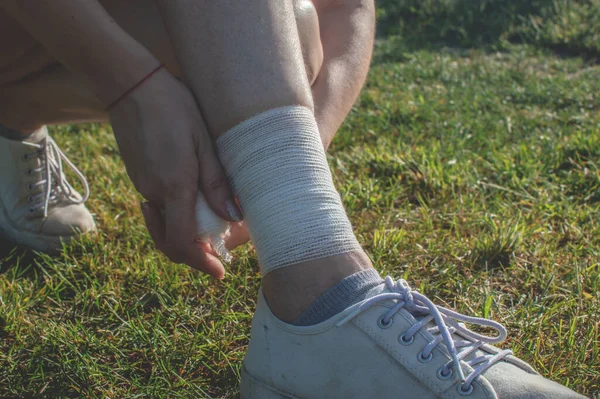 Self-bandaging. Young woman bandages her legs to protect tendons during. Ankle sprain pain
