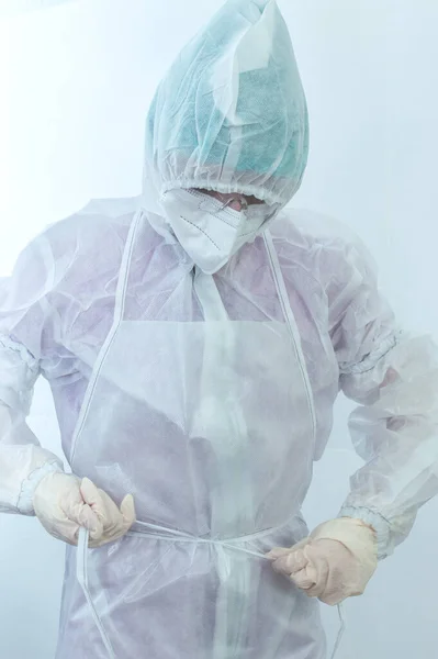 The process of putting on a medical protective anti-plague suit close-up. Young practitioner woman wearing protective medical suit to fight pandemic.