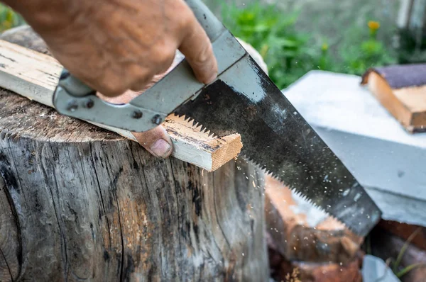 Ręka Mężczyzny Używa Piły Ręcznej Cięcia Kawałka Drewnianej Deski Opartej — Zdjęcie stockowe