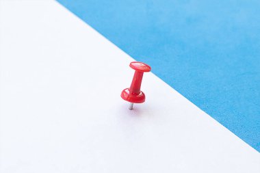 Kırmızı raptiyeli beyaz kağıdı mavi arka planda notlar için kapat. Yan görünüm