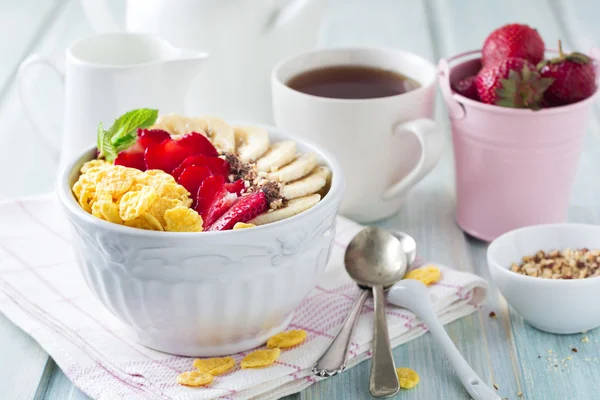 Gesundes Frühstück. Cornflakes, Banane, Erdbeere, Mandel, Schokolade und Joghurt in einer Keramikschale auf hellem Hintergrund. — Stockfoto