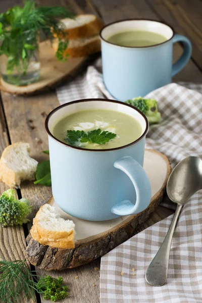 Soupe de brocoli et d'avocat tasse bleue en céramique sur le vieux fond de la table en bois. . — Photo