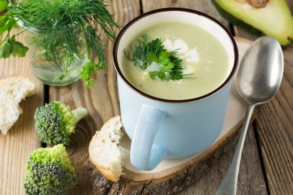 Suppe aus Brokkoli und Avocado Keramik blaue Tasse auf dem alten Holztisch Hintergrund. Selektiver Fokus. — Stockfoto