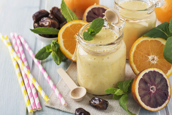 Healthy and fresh orange and date fruit smoothie on blue wooden table. Selective focus.
