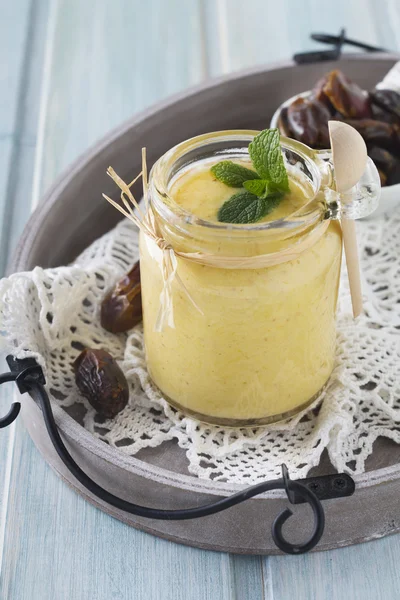 Healthy and fresh orange and date fruit smoothie on blue wooden table. Selective focus. — Stock Photo, Image