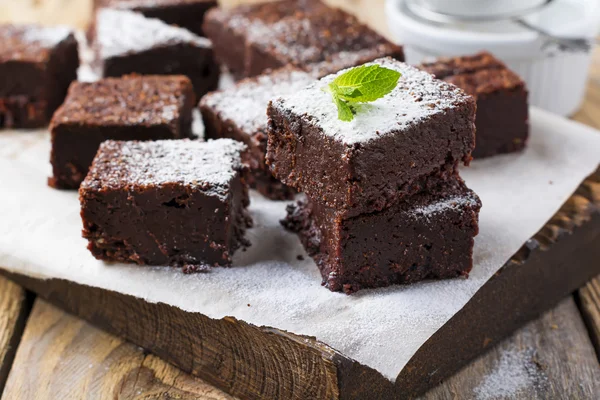 Chocolate brownies with powdered sugar and cherries on a dark wooden background. Selective focus. — Stock Photo, Image