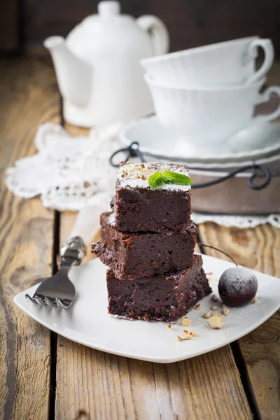 Brownies de chocolate con azúcar en polvo y cerezas sobre un fondo de madera oscura. Enfoque selectivo . —  Fotos de Stock