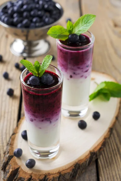 Taze sağlıklı blueberry smoothies çilek ve nane yaprakları bir ahşap stand ile bir cam. Seçici odak.