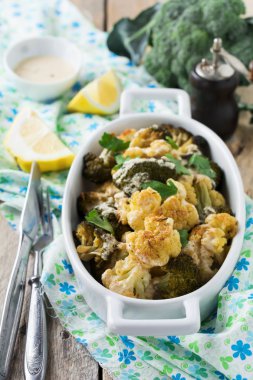 Karnabahar ve brokoli eski ahşap arka plan üzerinde beyaz bir seramik tabak içinde Tahin soslu pişmiş. Seçici odak.