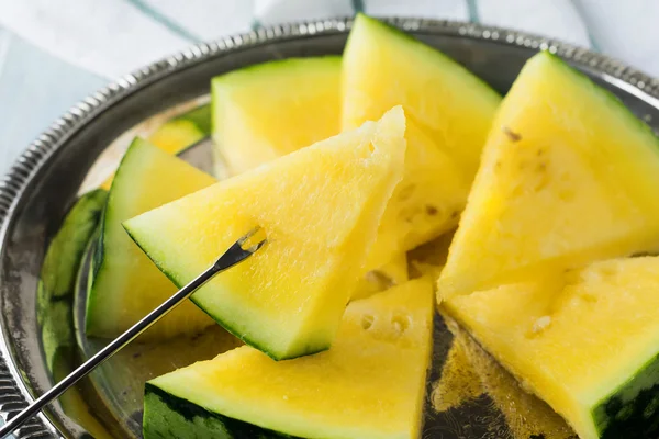 Hafif ahşap arka plan üzerinde demir tepsisindeki taze dilimlenmiş karpuz parçalar. Seçici odak.