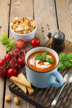 Eski ahşap arka plan üzerinde seramik bir fincan domates çorbası. Seçici odak.