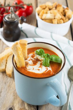 Eski ahşap arka plan üzerinde seramik bir fincan domates çorbası. Seçici odak.