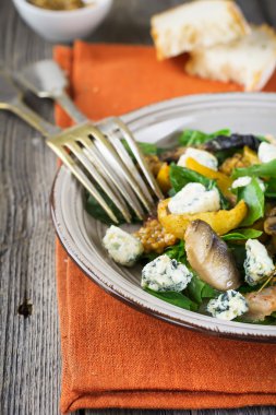 Patates, mantar, sosis, ıspanak, hardal sos ve peynir portakal peçete üzerinde sıcak sonbahar salatası. Eski ahşap arka plan. Seçici odak.