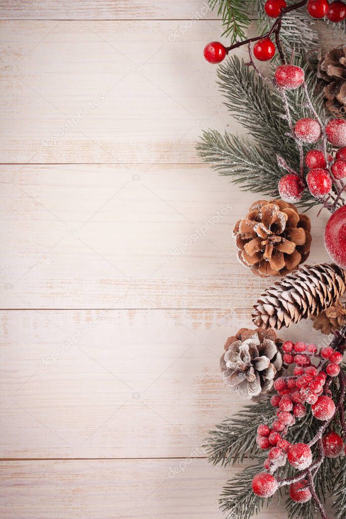 Christmas background with fir branches, pinecones and berries, glass and wooden xmas toys on the old wooden board. Retro stile.
