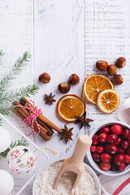 Pastanenin arka planında Noel pişirmek için malzemeler var. Un, esmer şeker, kızılcık ve baharatlar..
