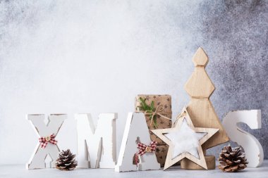 Tahta harfler XMAS ve dekoratif Noel ağacı, yıldız, koni, açık gri arka planda hediye kutusu. Sıfır israf Noel kavramı.