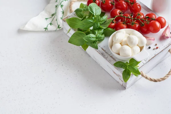 Polpette di mozzarella, pomodorini ciliegini e basilico biologico fresco verde. Ingredienti per la preparazione della cucina insalata italiana. — Foto Stock