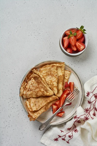 Beyaz seramik tabakta taze çilekli ev yapımı krepler. Üst görünüm.