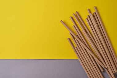 Kağıt ve mısır nişastasından yapılmış içme tüpleri, 2021 model sarı renk arka planda biyolojik olarak çözünebilir madde. Sıfır atık ve plastiksiz konsept. Üst görünüm.