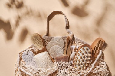 Sıfır atık, banyo aksesuarları saç fırçası, bambu diş fırçası, çubuk, sünger taşı, lif bezi, ahşap masaj aleti ve yeniden kullanılabilir bej arka planda doğal sabun. Üst görünüm.