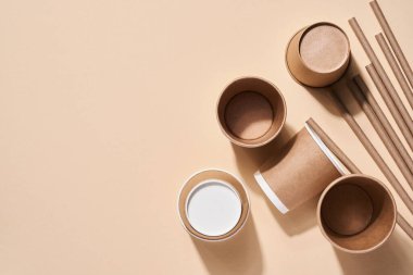 Ev kullanımı, bambu ya da kağıt kamış, tek kullanımlık fincanlar ve plajdaki yaprakların gölgesiyle bej üzerine ahşap kahve karıştırıcıları için yenilenebilir bireysel nesneler. Sıfır kayıp. Üst görünüm.