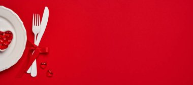 Sevgililer Günü arkaplanı ya da boş beyaz plakalı konsept içinde küçük kalpler olan küçük kalp şeklinde bir tabak ve kırmızı ya da kırmızı arka planda beyaz eşya. Pankart. Kopyalama alanı olan üst görünüm.