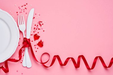 Sevgililer Günü arkaplanı ya da içi boş beyaz plakalı konsept içinde küçük kalpler olan küçük kalp şeklinde bir tabak ve pembe arka planda beyaz yazılımlar. Kopyalama alanı olan üst görünüm.
