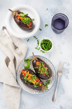 Farklı sebzelerle doldurulmuş patlıcan, domates, biber, soğan, mikroyeşillik ve gri taş ya da beton masa zemininde maydanoz. Üst görünüm.