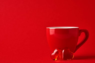 Kırmızı bardak bardak ve kırmızı arka planda iki çikolata kalp. Düz kompozisyon. Sevgililer Günü konsepti. Üst görünüm, alanı kopyala.