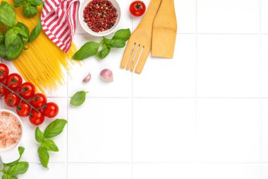 Parmesan peynirli ve domatesli çiğ spagetti, fesleğen, sarımsak ve arka planda hafif arka planda biberli yağ. İtalyan makarnası hazırlamak için geleneksel malzemeler. Üst görünüm.