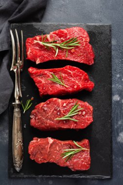 Et eti. Baharatlı, soğanlı ve biberiyeli dört taze çiğ biftek. Üst görünüm