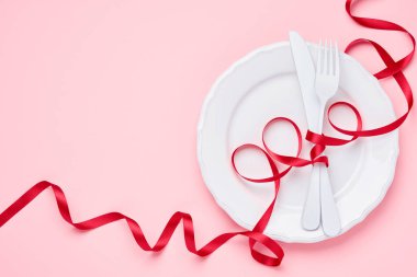 Sevgililer Günü arkaplanı ya da içi boş beyaz plakalı konsept içinde küçük kalpler olan küçük kalp şeklinde bir tabak ve pembe arka planda beyaz yazılımlar. Kopyalama alanı olan üst görünüm.