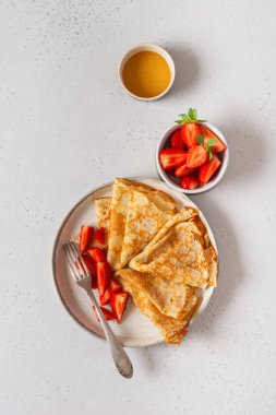 Tatil için geleneksel yemek Maslenitsa. Ballı ince krep, taze çilek ve kahvaltı hazırlamak için malzemeler. Üst görünüm.