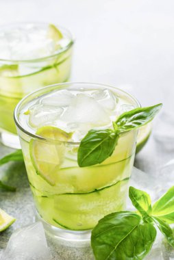 Limon, limon, salatalık ve eski beton arka planda buzlu fesleğenden yapılan ev yapımı limonata ferahlatıcı. Seçici odak.