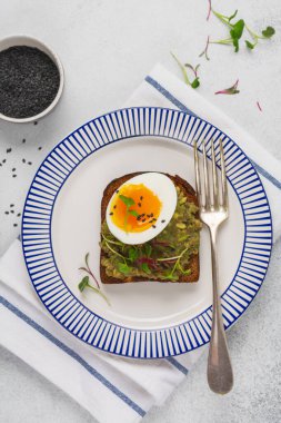 Healthy sandwich with avocado, eggs and microgreens on toast on a serving plate for breakfast. Healthy nutrition dietary concept. Top view. clipart