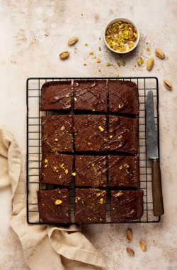Fıstık fıstıklı çikolata kareleri ve metal bir standın üzerinde çilek, ışık taşı arka plan, üst manzara, yatay kompozisyon. Düz yatıyordu.