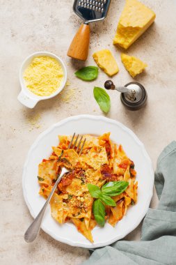 Klasik domates soslu makarna, parmesan ve fesleğen ve kırsal beton ışıklı masa arkaplanı. Geleneksel İtalyan yemeği servisi. Üst görünüm.